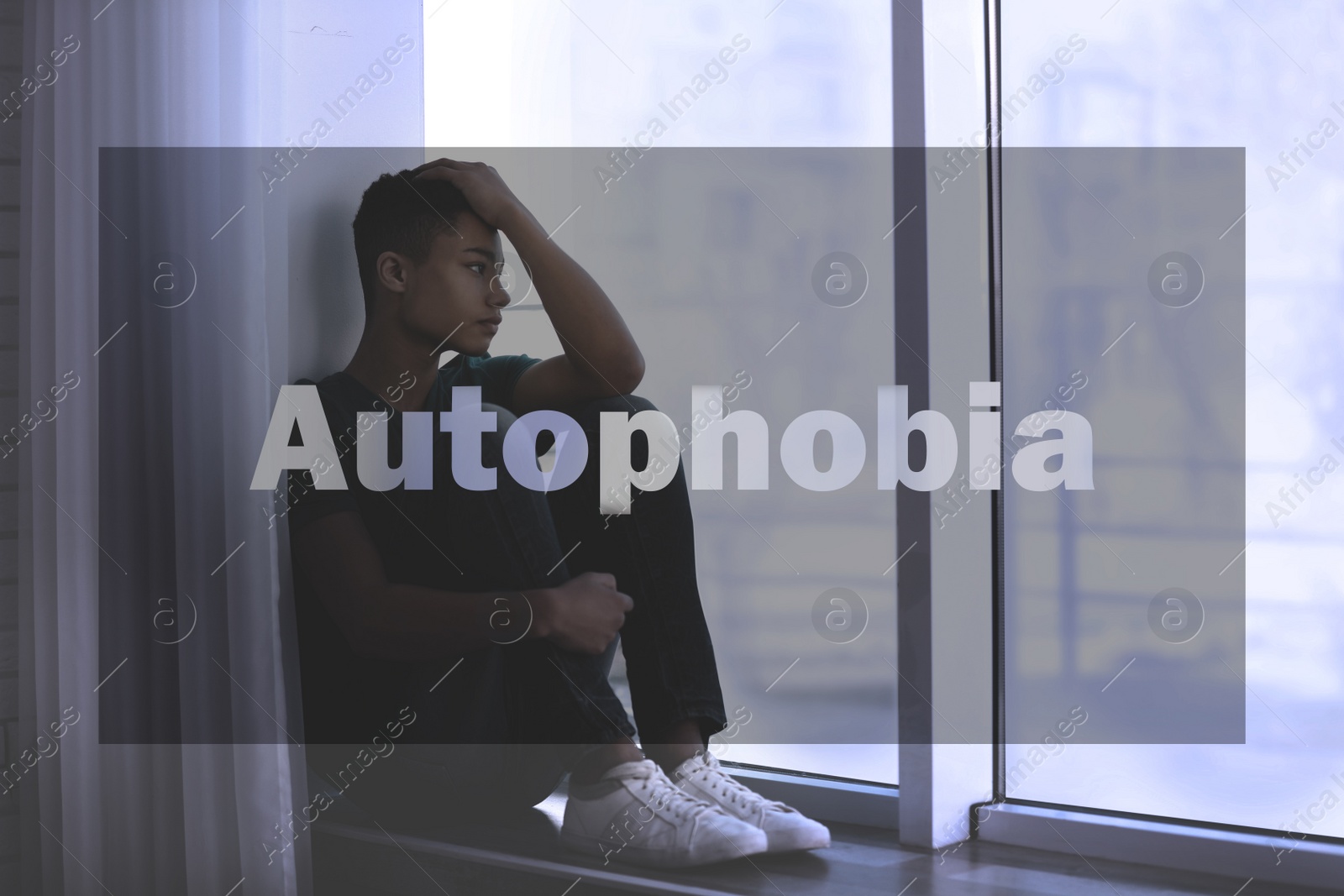 Image of Depressed African-American teenage boy sitting alone near window. Autophobia - fear of isolation