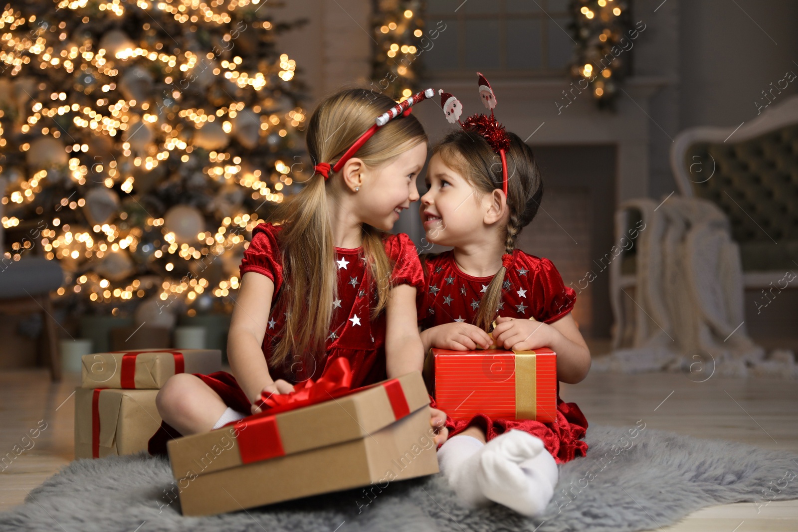 Photo of Cute little children with Christmas gifts in living room