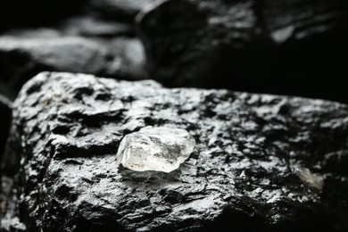 Photo of Shiny rough diamond on stone surface. Space for text