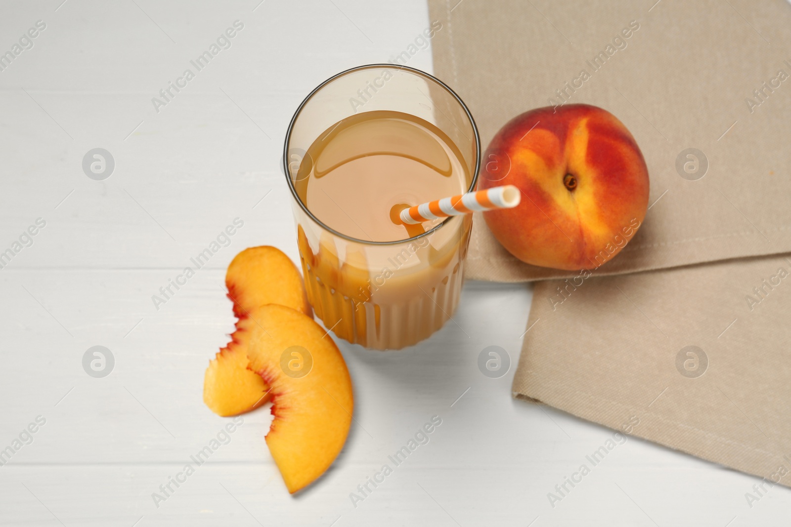 Photo of Glass of delicious peach juice and fresh fruits on white wooden table, above view