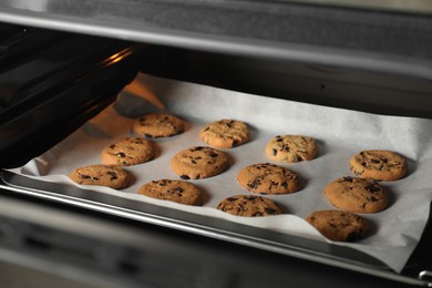 Baking delicious chocolate chip cookies in oven, closeup
