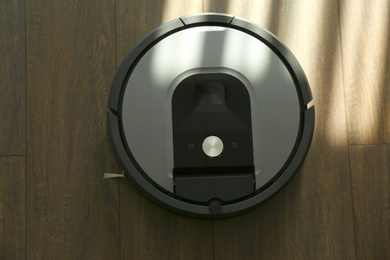 Modern robotic vacuum cleaner on wooden floor, top view