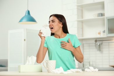 Photo of Young woman suffering from allergy in kitchen