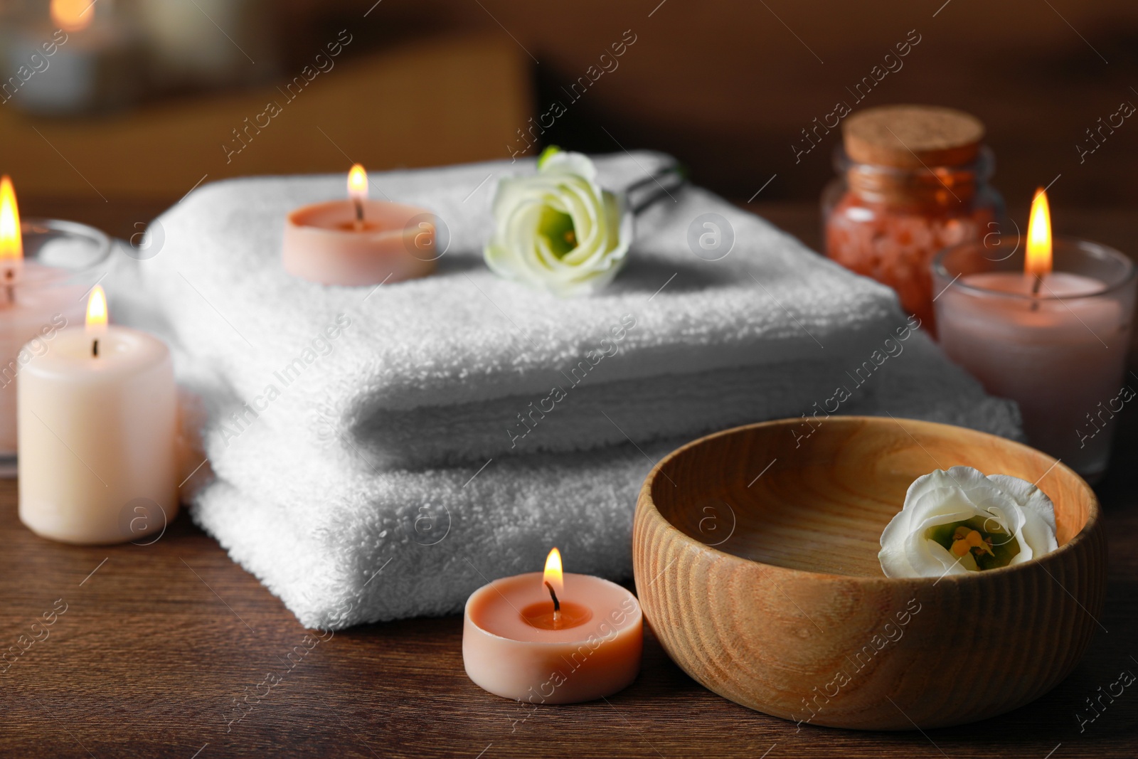 Photo of Beautiful spa composition with burning candles and flowers on wooden table