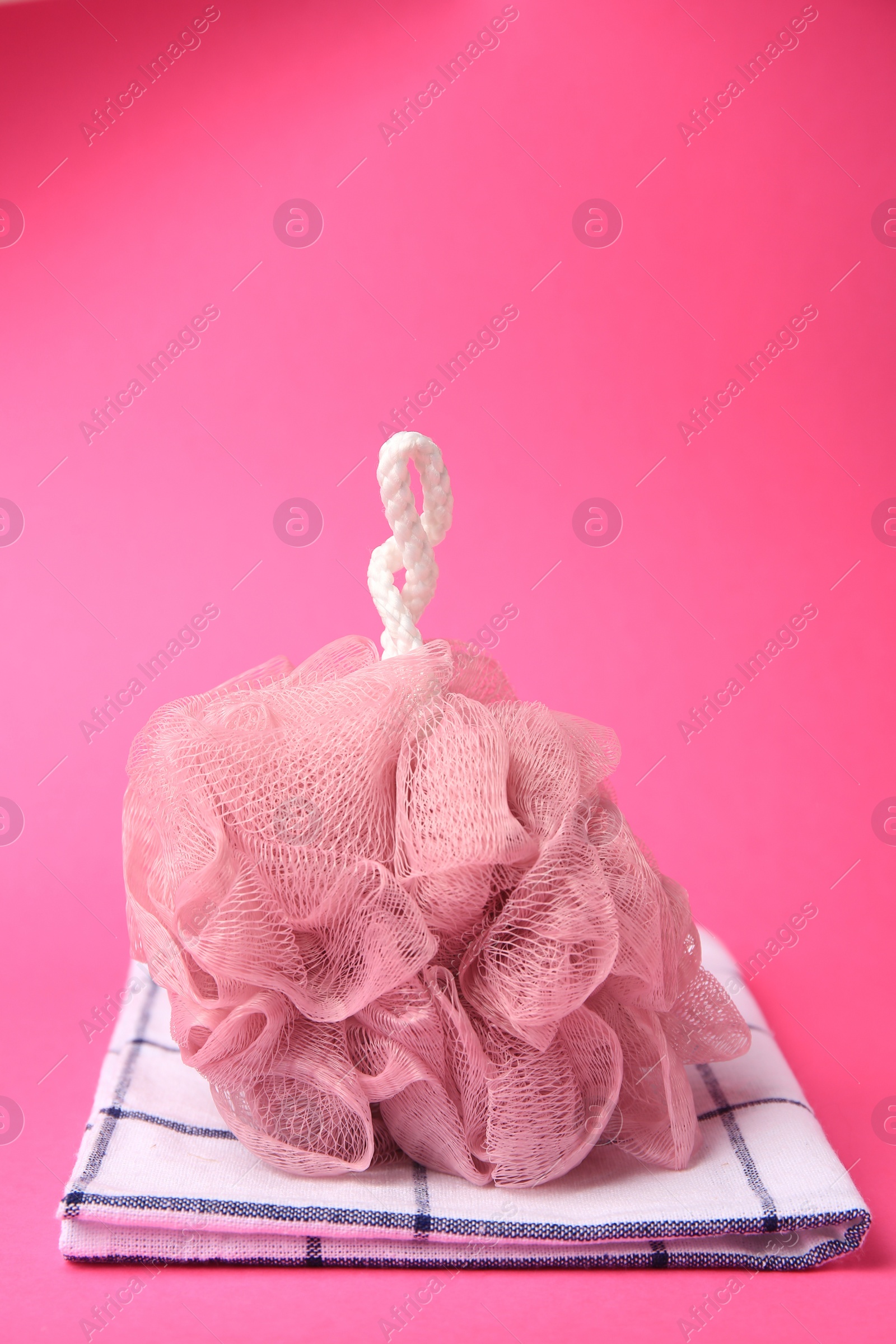 Photo of New shower puff and towel on pink background, space for text