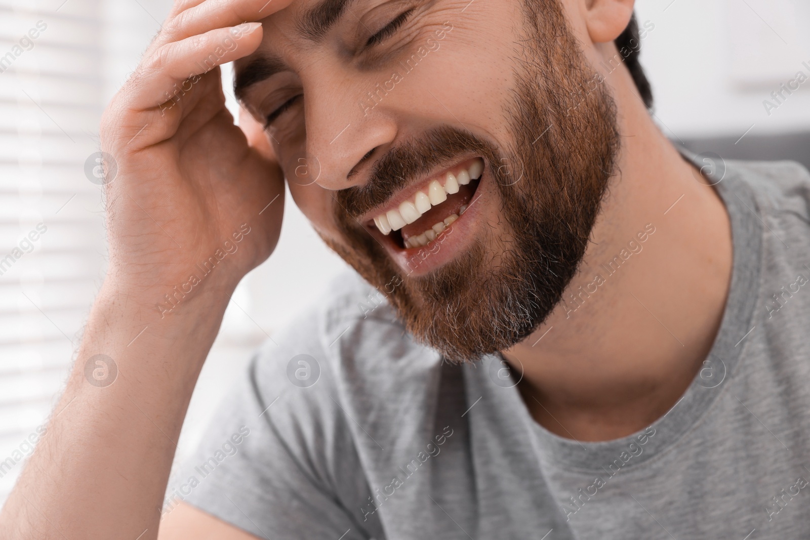 Photo of Portrait of handsome man laughing at home, closeup