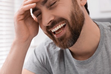 Photo of Portrait of handsome man laughing at home, closeup