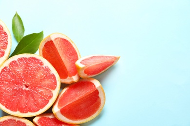 Fresh grapefruits and leaves on color background, flat lay with space for text. Citrus fruits