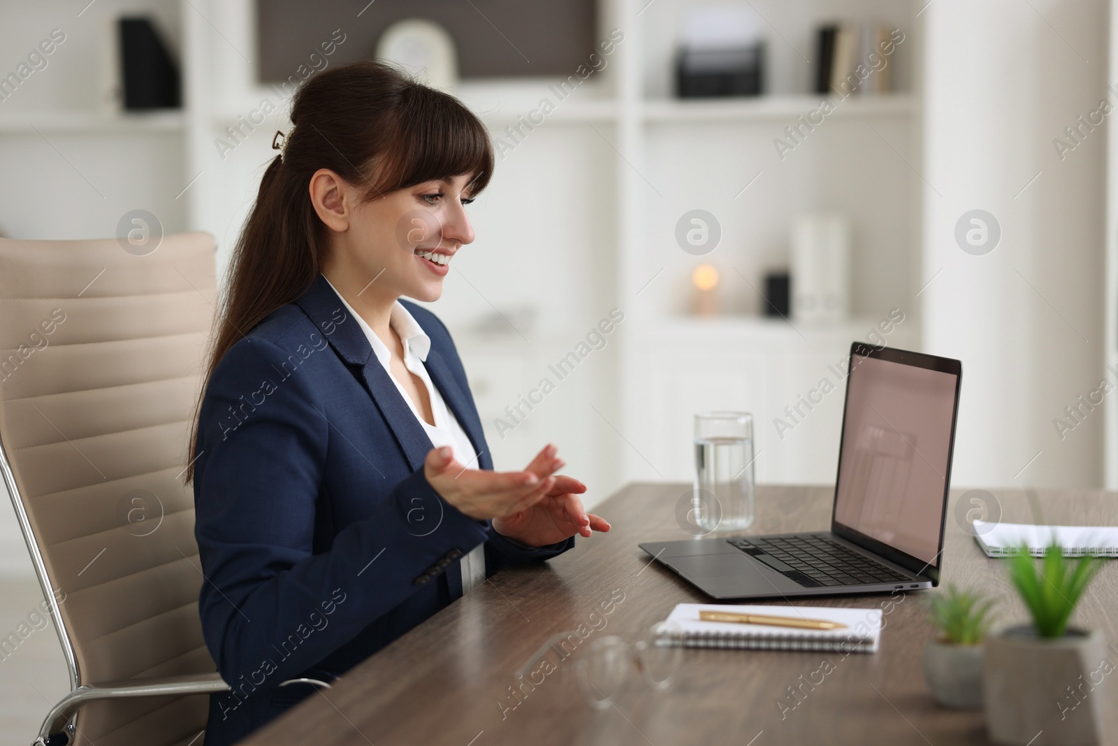 Photo of Woman using video chat during webinar at wooden table in office