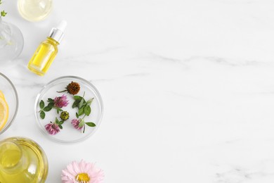 Cosmetic oil and flowers on white marble table, flat lay. Space for text