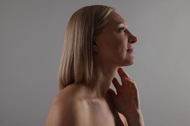 Photo of Beautiful woman touching her neck on grey background