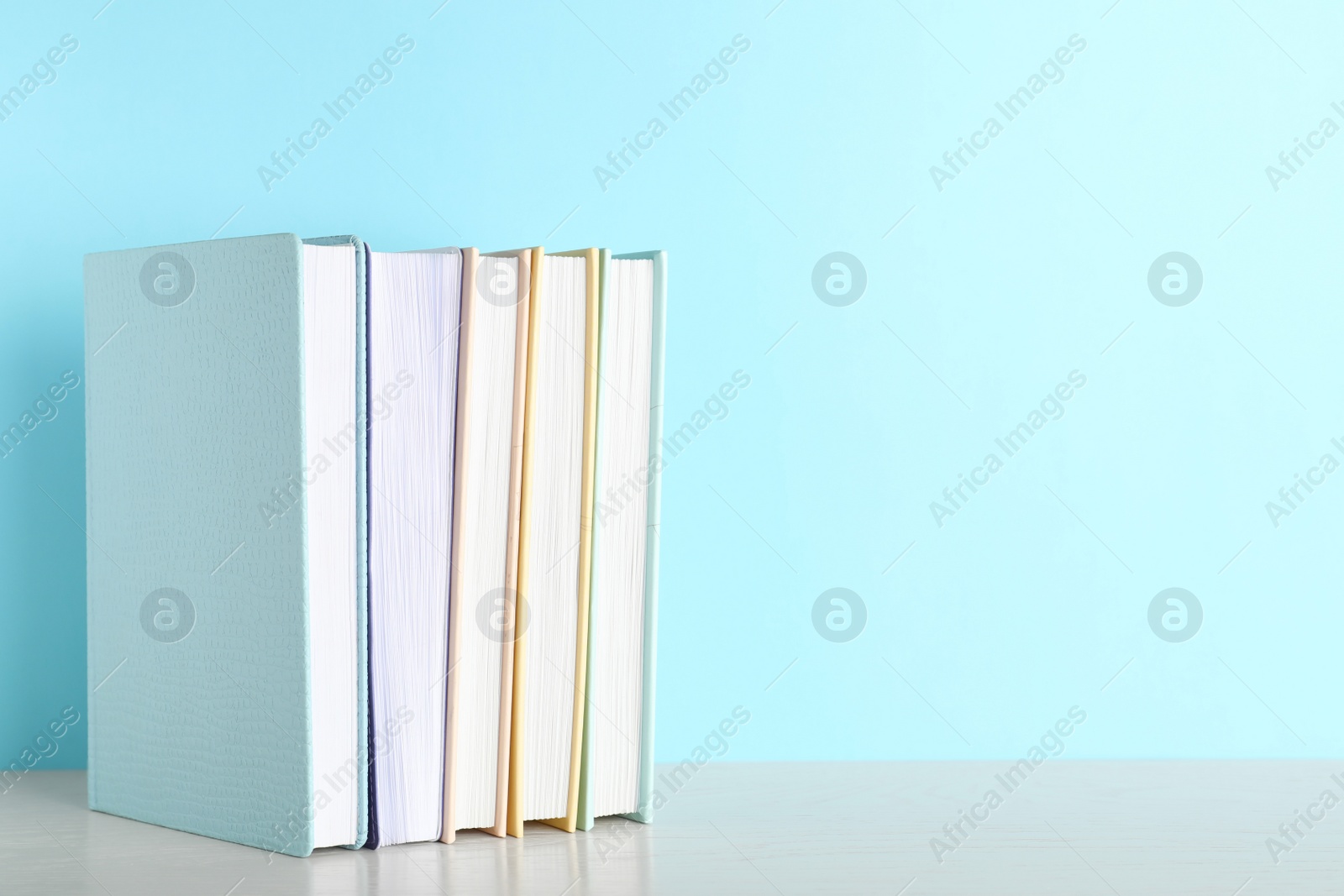 Photo of Hardcover books on table against color background, space for text