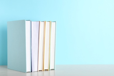 Photo of Hardcover books on table against color background, space for text