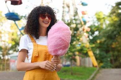 Photo of Portrait of happy woman with cotton candy at funfair. Space for text