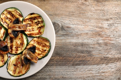 Photo of Grilled zucchini slices on wooden background, top view. Space for text