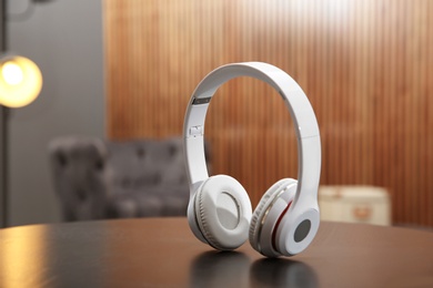 Photo of Stylish headphones on table against blurred background