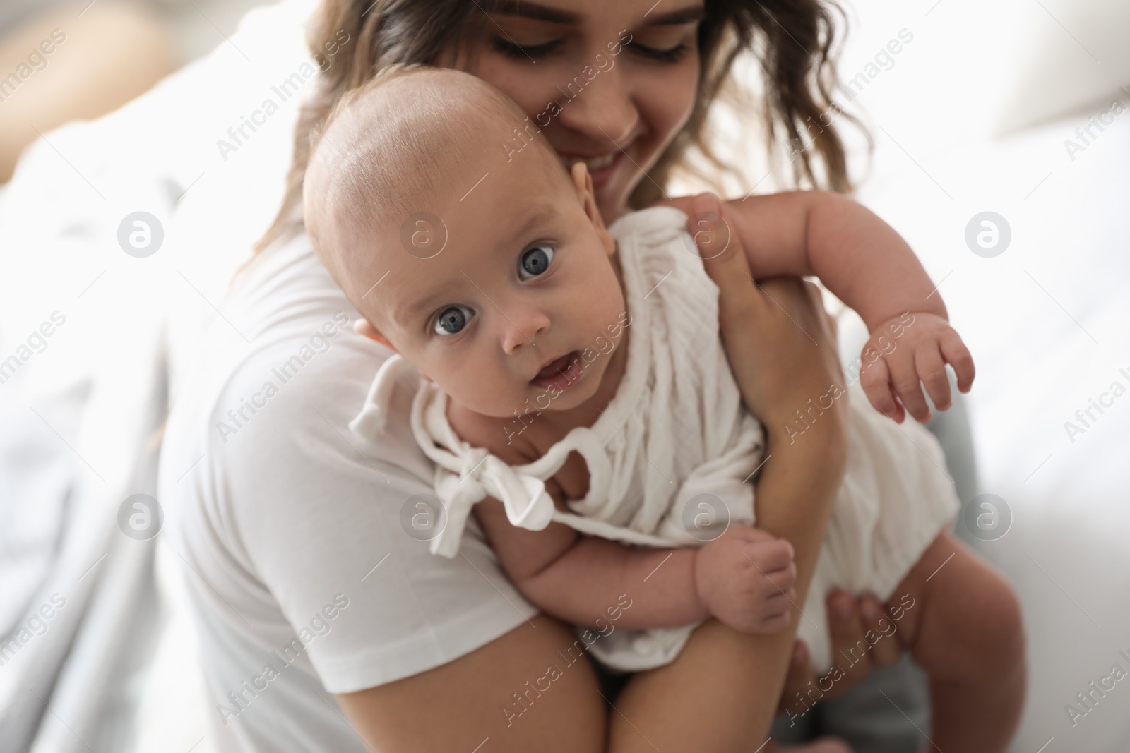 Photo of Happy young mother with her cute baby on bed, closeup