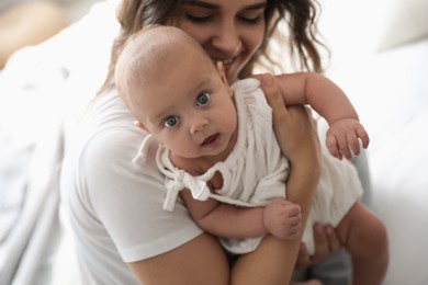 Happy young mother with her cute baby on bed, closeup