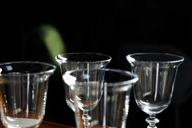 Photo of Empty clean glasses on dark background, closeup