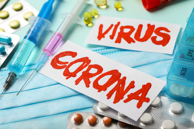 Photo of Phrase CORONA VIRUS and medicines on light blue background