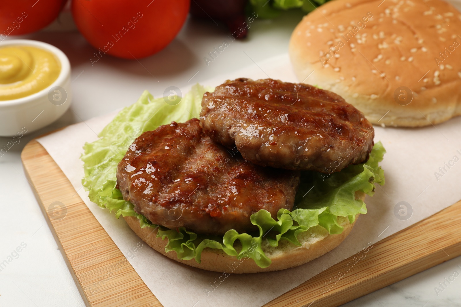 Photo of Delicious fried patties, lettuce and bun on white table, closeup. Making hamburger