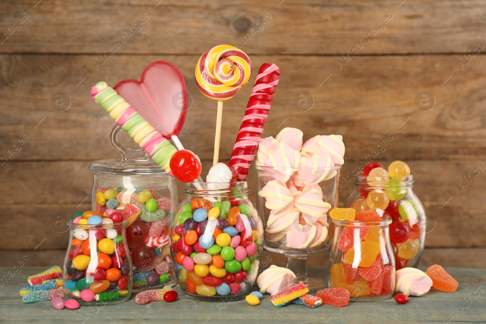Photo of Jars with different delicious candies on light blue wooden table