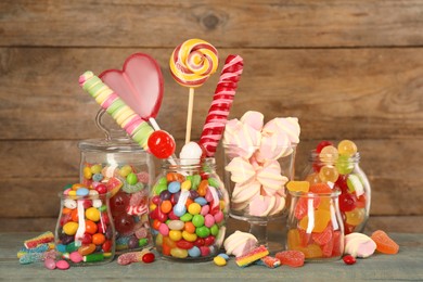 Jars with different delicious candies on light blue wooden table