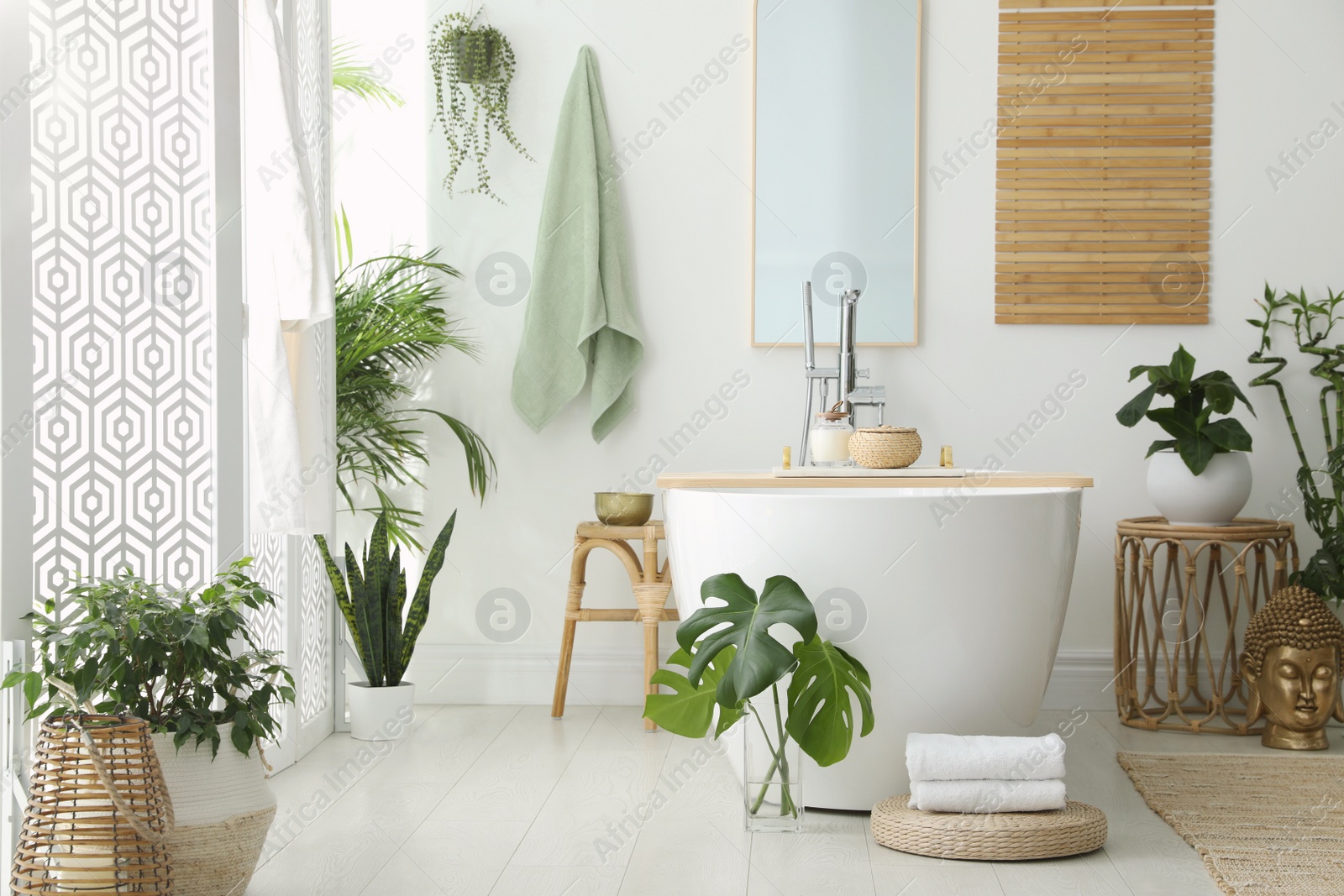 Photo of Stylish bathroom interior with modern tub, houseplants and beautiful decor. Home design