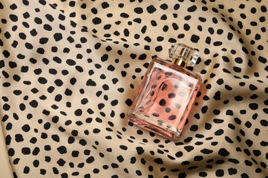 Photo of Luxury perfume in bottle on fabric with leopard pattern, top view