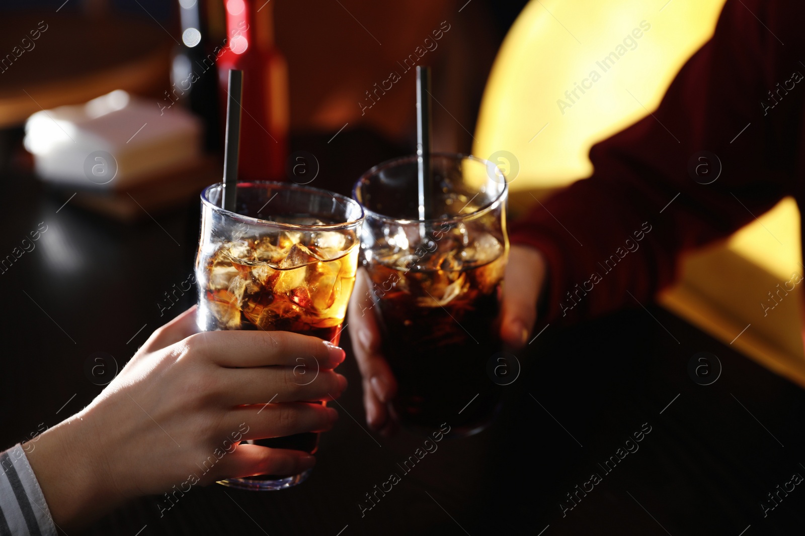 Photo of Young couple with glasses of refreshing cola at table indoors, closeup