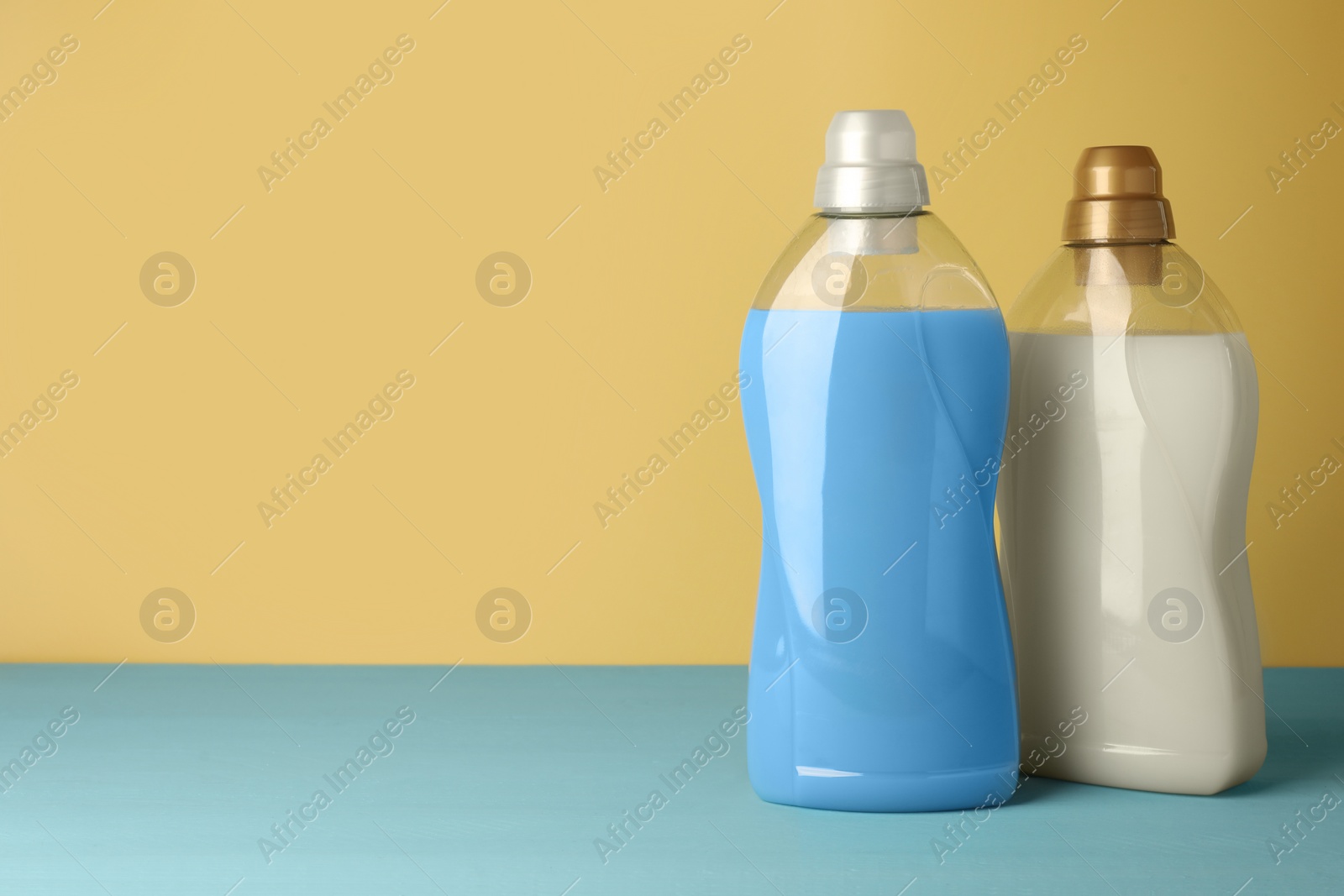 Photo of Bottles of fabric softener on light blue table, space for text