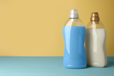 Photo of Bottles of fabric softener on light blue table, space for text