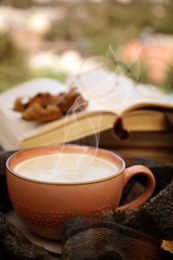 Image of Cup of hot coffee and warm scarf on window sill indoors