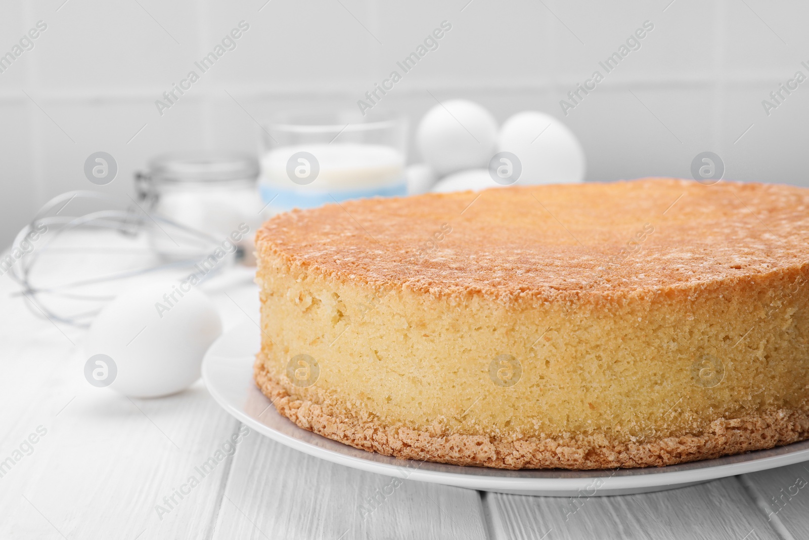 Photo of Plate with delicious sponge cake on white wooden table, closeup