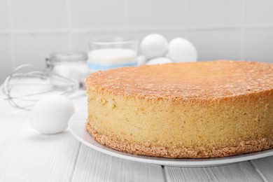 Plate with delicious sponge cake on white wooden table, closeup