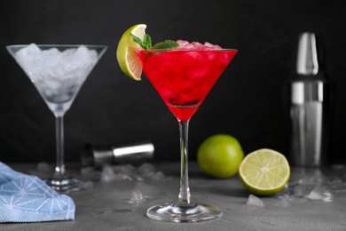 Photo of Tasty red alcoholic cocktail in martini glass on light grey table