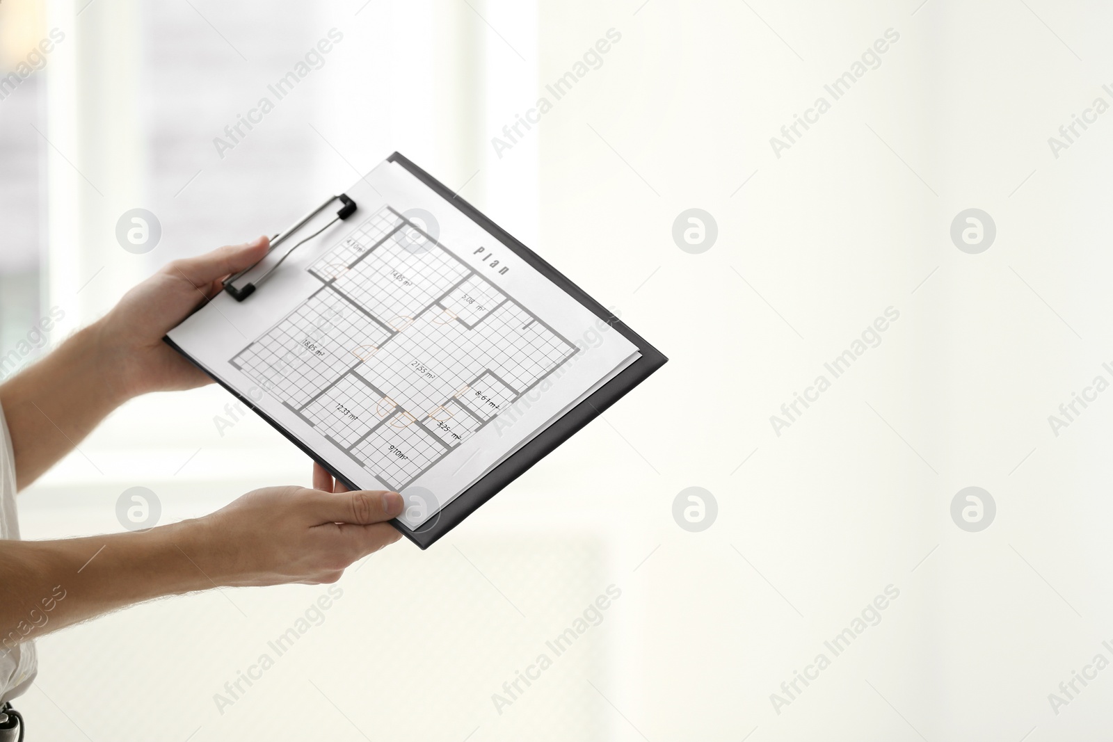 Photo of Professional interior designer with clipboard on light background, closeup