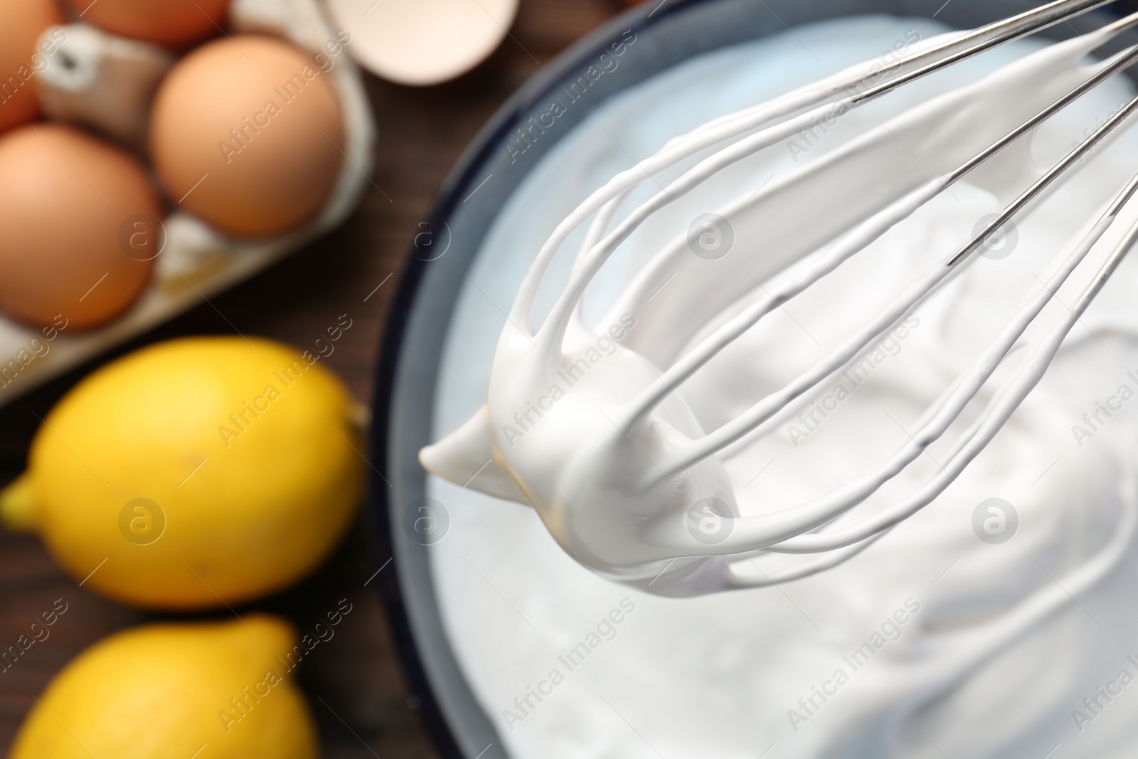 Photo of Whisk with whipped cream over bowl, top view