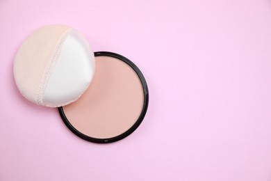 Face powder and puff on pink background, flat lay. Space for text