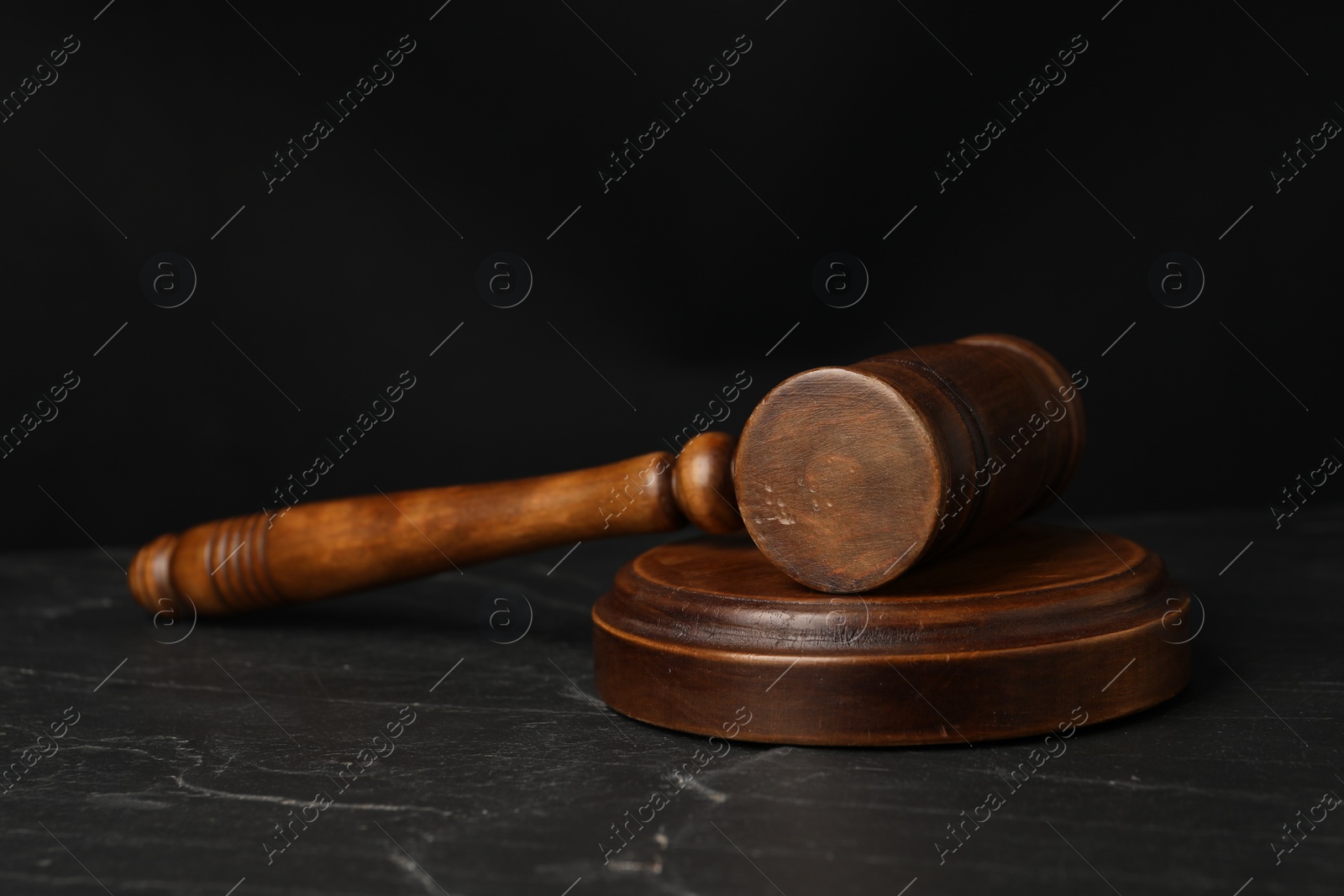 Photo of Wooden gavel on dark textured table, closeup