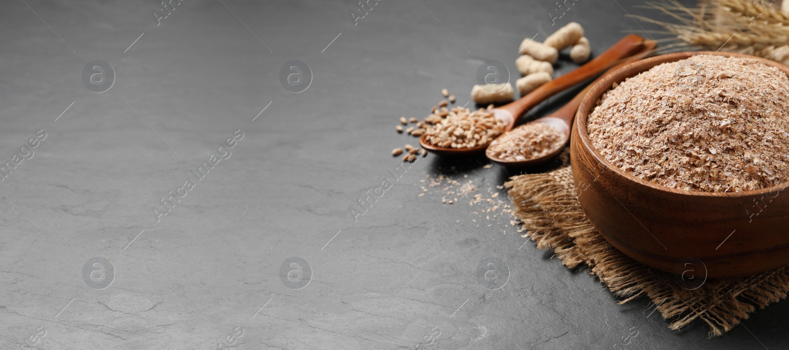 Photo of Wheat bran in bowl on black table. Space for text