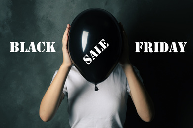 Black Friday concept. Woman holding balloon with text SALE on dark background