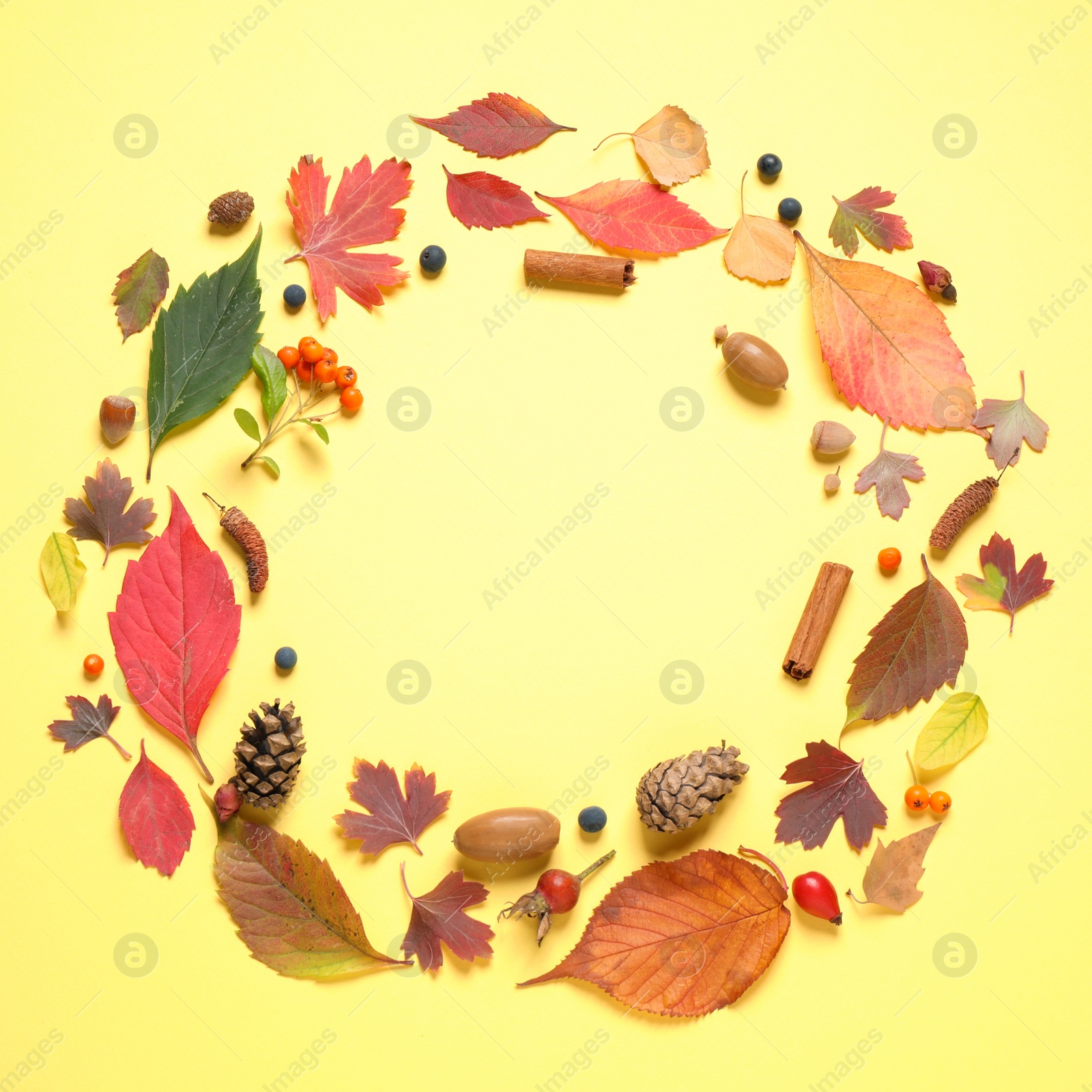 Photo of Frame made of autumn leaves on yellow background, top view. Space for text