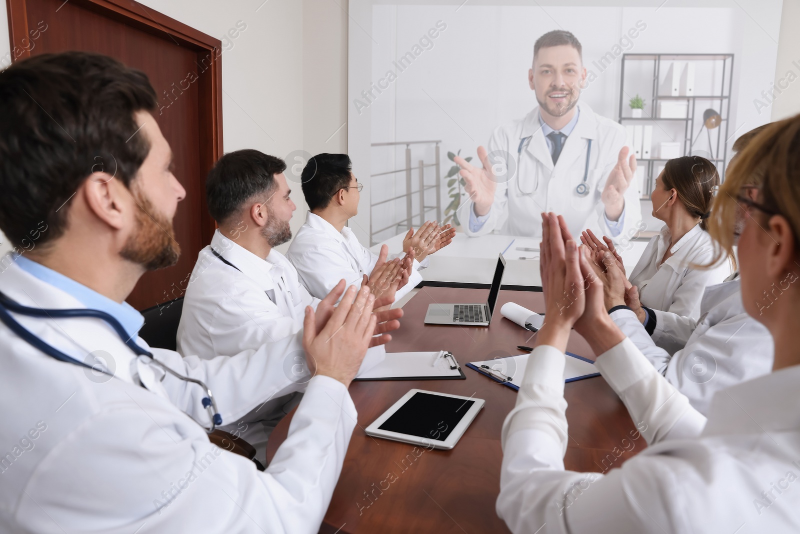 Image of Lecture with online participant. Doctors in meeting room. Using projector for videoconference