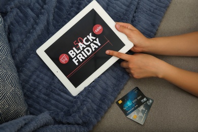 Photo of Woman with credit cards using tablet for online shopping on sofa, top view. Black Friday sale