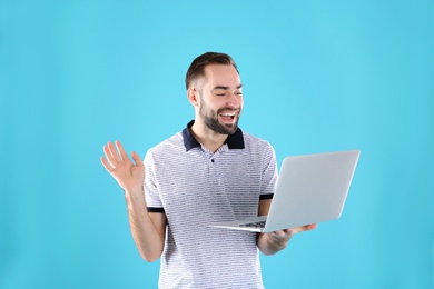 Photo of Man using laptop for video chat on color background