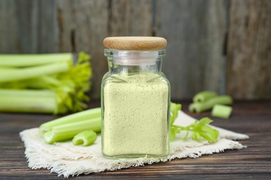 Photo of Natural celery powder in jar and fresh stalks on wooden table