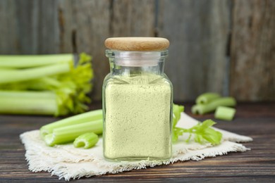 Natural celery powder in jar and fresh stalks on wooden table