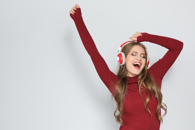 Young woman listening to Christmas music on color background