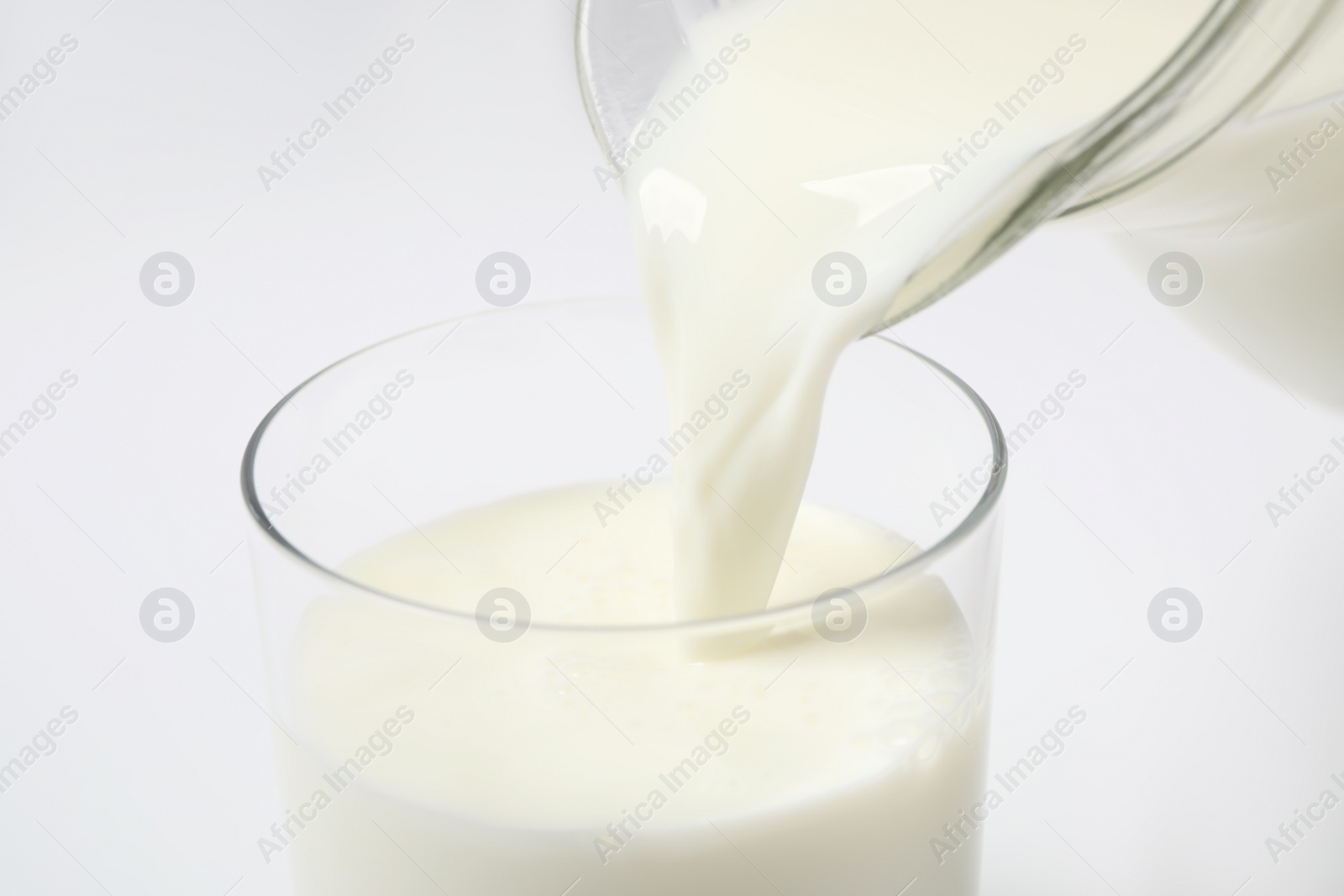 Photo of Pouring milk into glass on white background, closeup